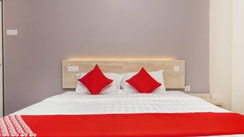 A neatly made bed with a red and white bedspread and two red pillows.