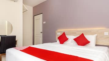 Una habitación de hotel con cama, escritorio, silla, espejo y puerta.