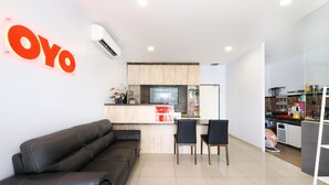 A modern reception area with a black leather couch, two black chairs, a wooden counter, and a TV. - OYO 778 BMW 2 Hotel (Muar)