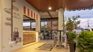 A modern hotel lobby with a reception desk, directional signs, and potted plants. - OYO 778 BMW 2 Hotel (Muar)