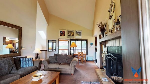 A spacious living room with a fireplace, sofas, and a dining area.