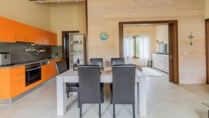 Eine moderne Küche mit orangefarbenen Schränken und einem Essbereich mit einem weißen Tisch und schwarzen Stühlen.