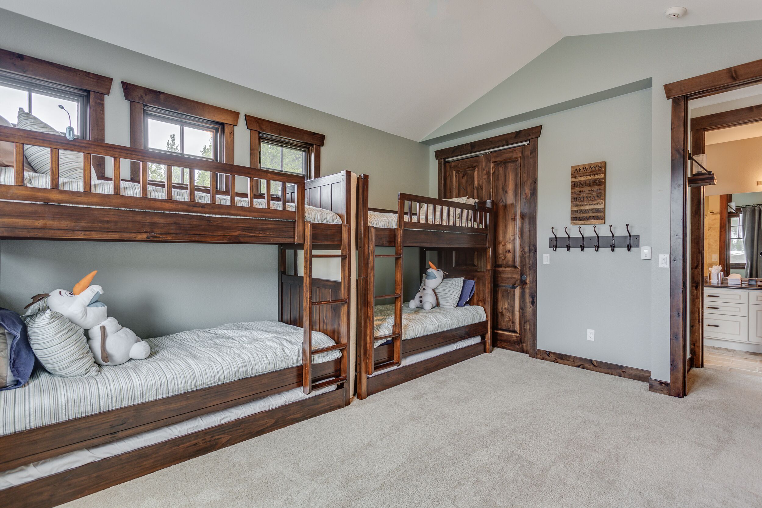 Une chambre avec des lits superposés, une tête de lit en bois, une fenêtre et un porte-manteau fixé au mur.
