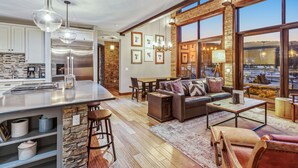 Un vaste espace de vie doté d’un grand îlot central, d’éléments décoratifs en pierre et offrant une vue sur l’extérieur.