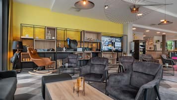 A modern lounge area with leather sofas, a wooden coffee table, and a large TV screen displaying content.