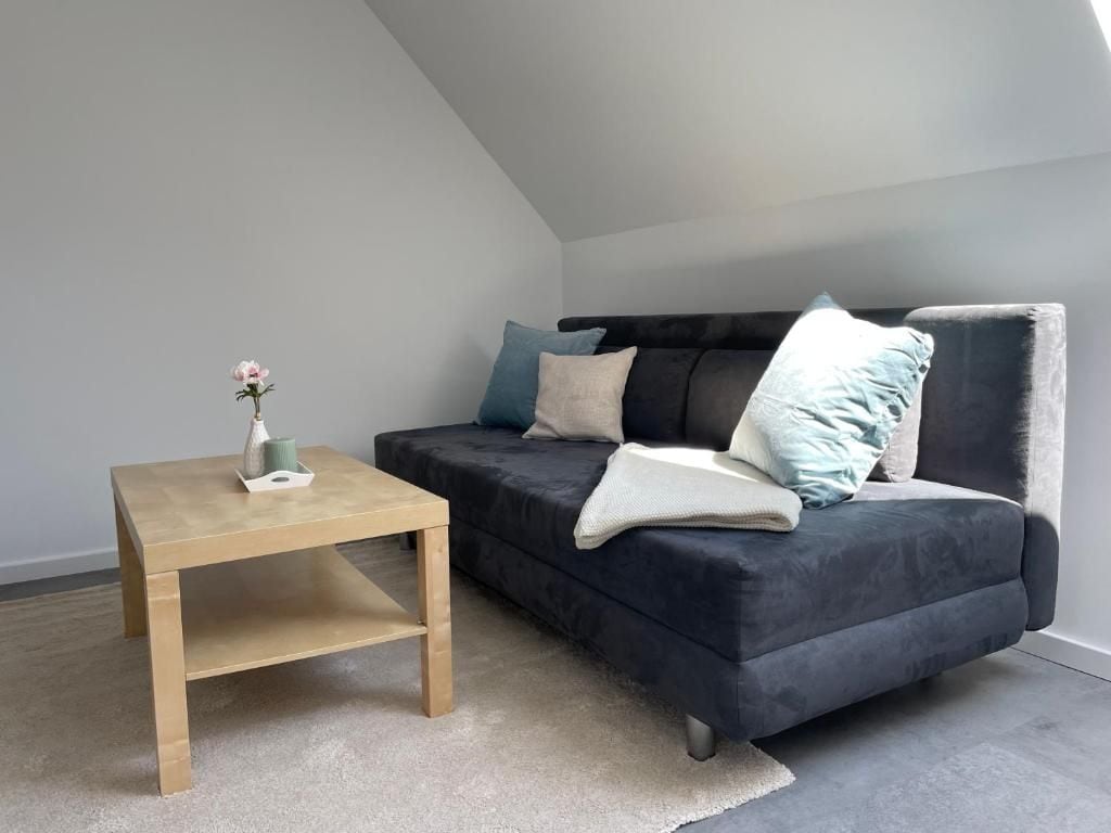 A modern living room with a dark sofa, a wooden coffee table, and a vase with a single flower.