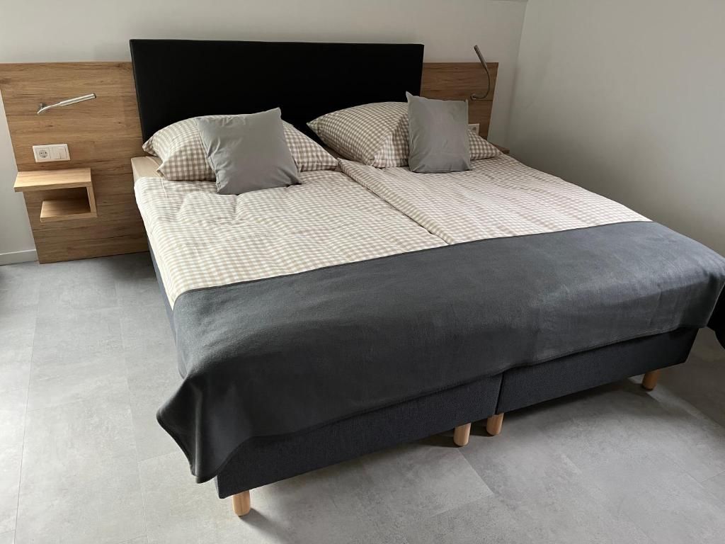 Una cama con colcha a cuadros, cabecera oscura y mesita de noche con lámpara.