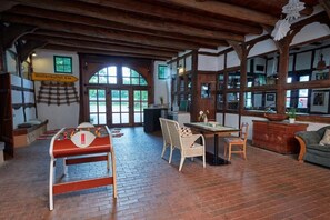 A rustic interior with a foosball table, wooden furniture, and a large window. - Reiterhof Zwei Linden (Melle)