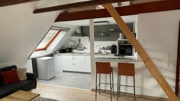 Ein Loft-Wohnraum mit Küche, einem Essbereich mit zwei Stühlen und einer Couch mit Couchtisch.