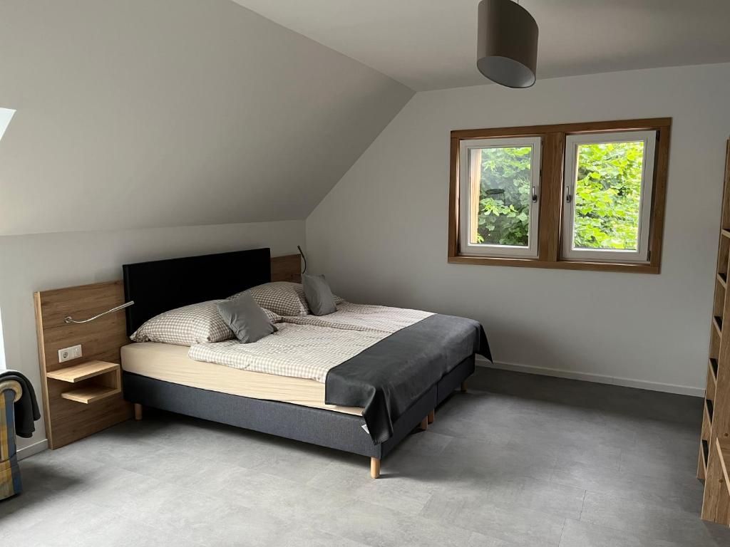Een slaapkamer met een bed, nachtkastjes, een garderobe en een raam met uitzicht op groen.