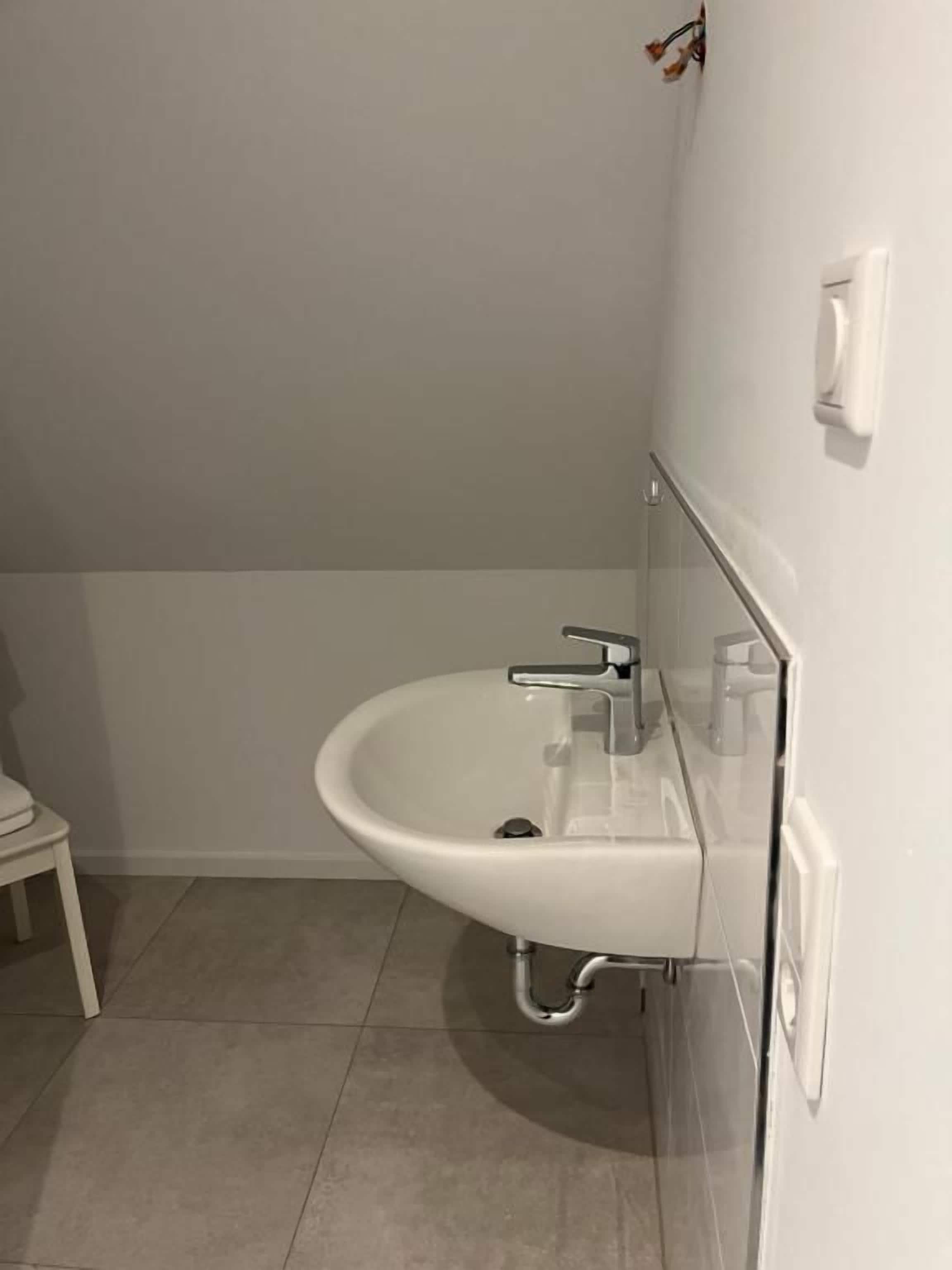 A bathroom with a white sink, a mirror, and a white toilet.