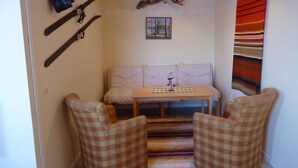 A cozy room with a sofa, two plaid armchairs, a small table, and a painting on the wall. - Sopperogården - Hostel (Övre Soppero)