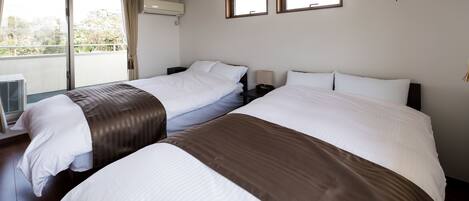 A hotel room with two beds, a large window, and a ceiling fan.