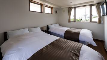 A hotel room with two beds, a TV, and large windows with curtains.