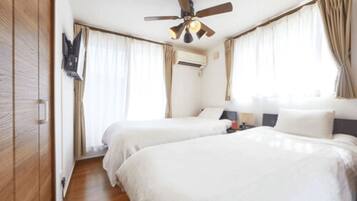 A hotel room with two beds, a ceiling fan, and a mounted TV.