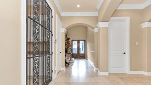 Un pasillo con una reja metálica decorativa, una puerta blanca y un arreglo floral.
