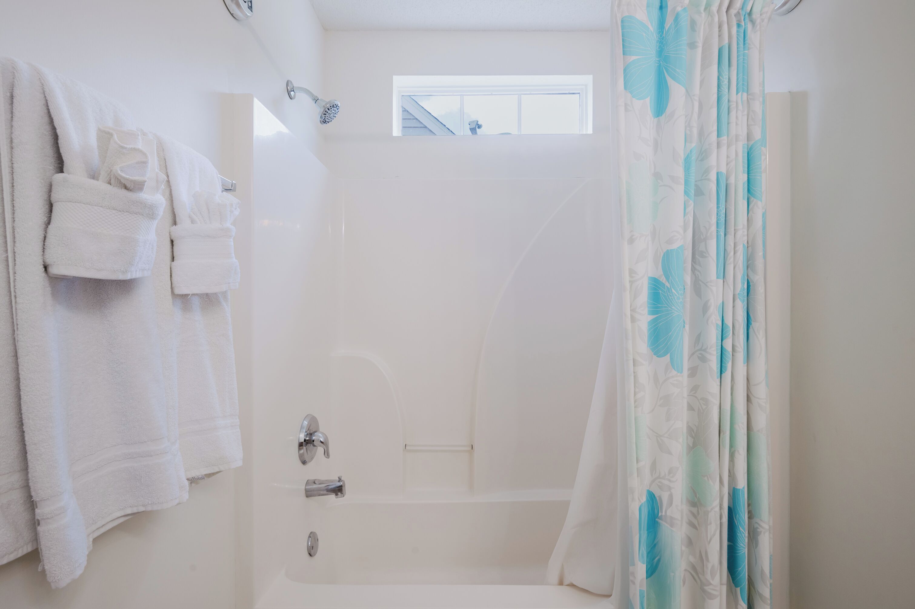 A bathroom with a bathtub, a shower, and a window.