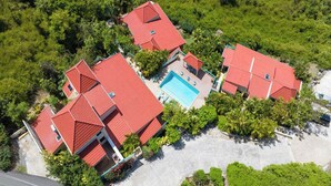 Ein Luftbild eines Resorts mit mehreren Gebäuden, einem Schwimmbad und üppiger Bepflanzung.