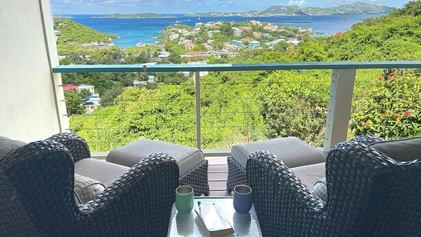 Ein Balkon mit Korbmöbeln, einem Tisch und zwei Tassen.
