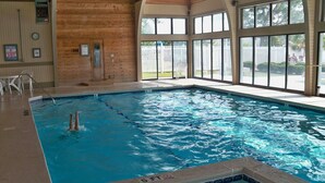 Una piscina interior con agua cristalina, paredes de madera y amplios ventanales.