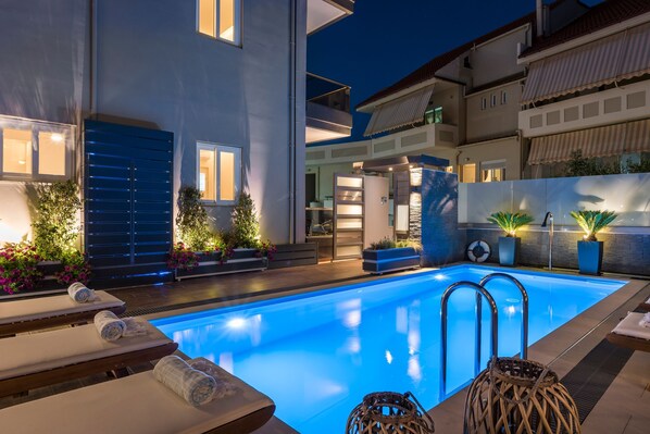 A modern pool area with lounge chairs and a clear blue pool. - Sun Ray Luxury Apartments (Chania)