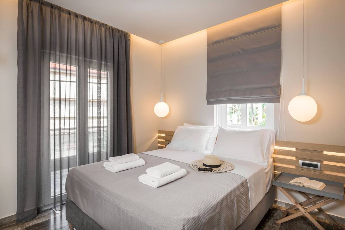 A modern hotel room with a large bed, a bedside table, and a window with curtains.