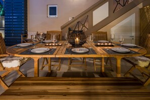 A dining table set for six with candles, a decorative lantern, and wooden chairs. - Sun Ray Luxury Apartments (Chania)