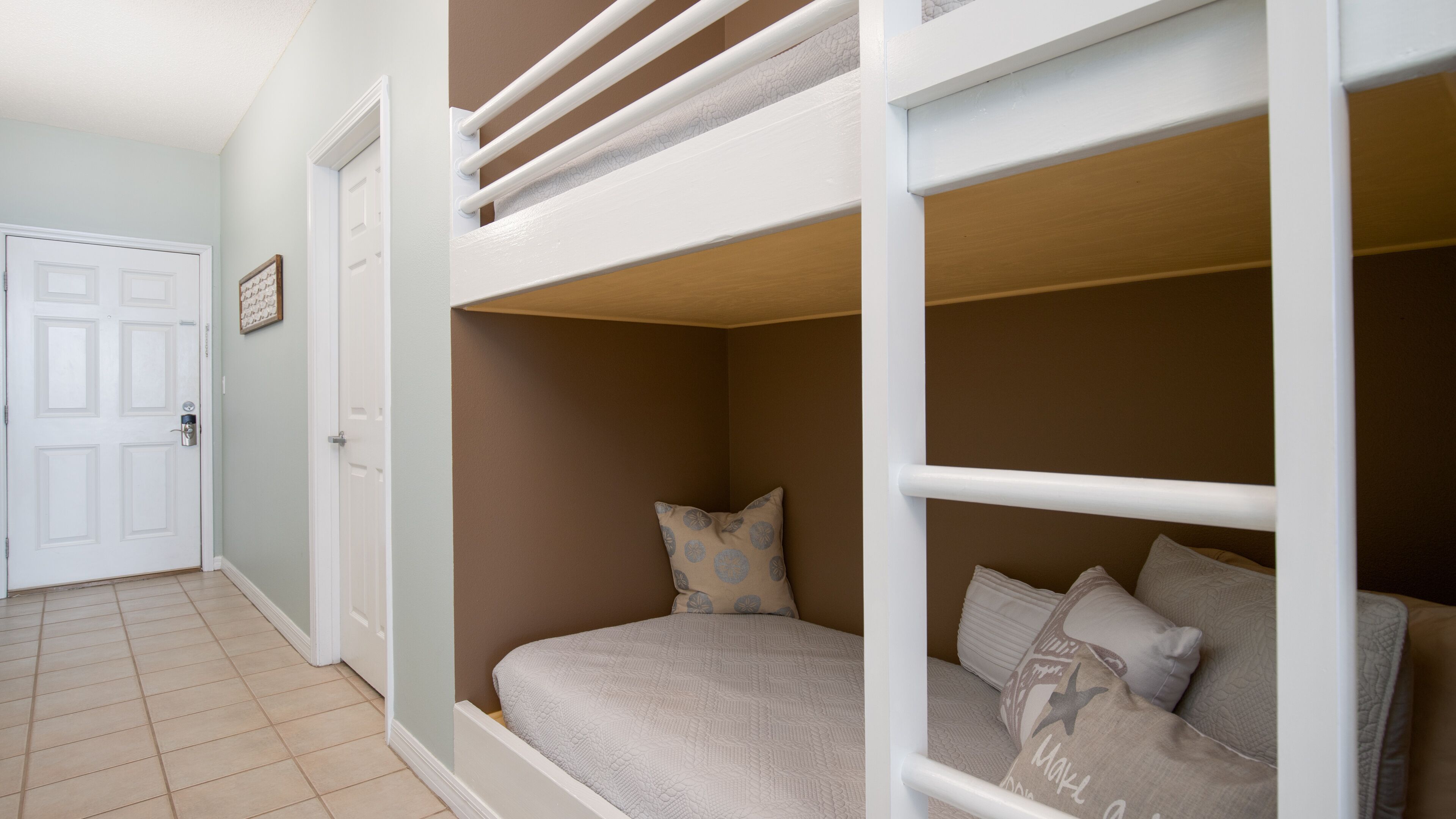 A room with bunk beds, a door, and a tiled floor.