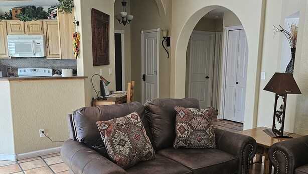 A living room with a brown leather sofa, patterned throw pillows, a wooden coffee table, and a tiled floor. - Cozy Sedona Get-Away (Sedona)