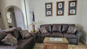 A living room with a brown leather sofa, two matching armchairs, a wooden coffee table, and three framed artworks on the wall. - Cozy Sedona Get-Away (Sedona)