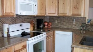 A kitchen with wooden cabinets, a microwave, stove, and dishwasher. - Cozy Sedona Get-Away (Sedona)