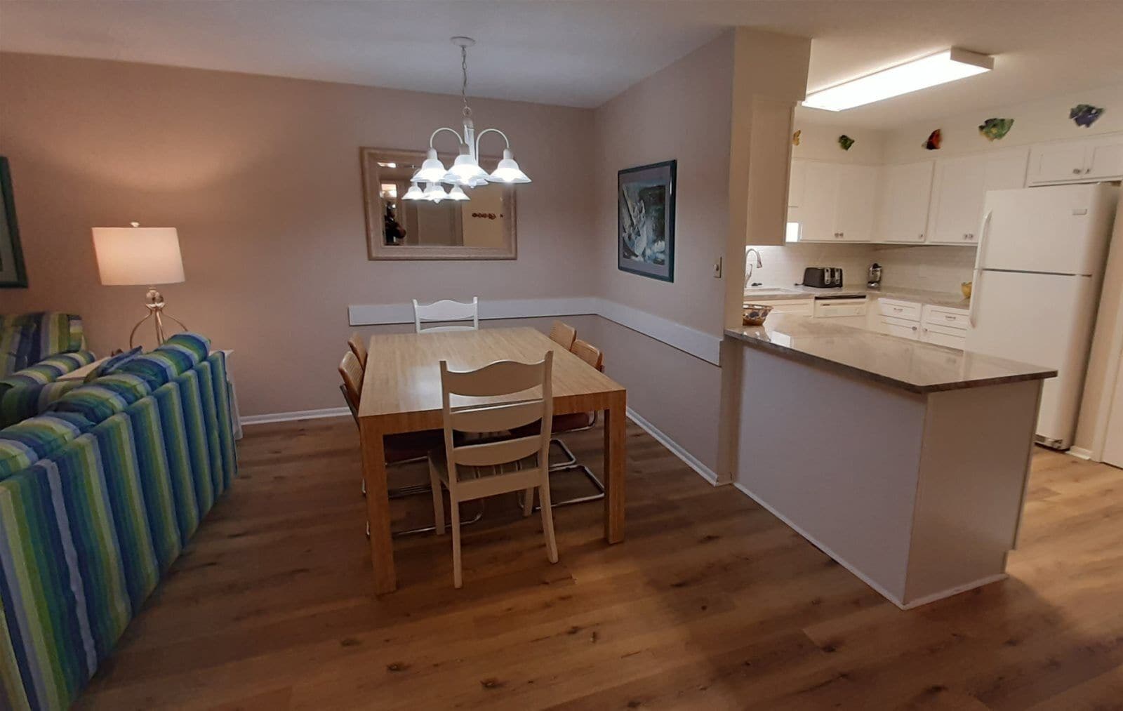 Cocina compacta con una mesa de comedor, sillas, una pequeña isla y un sofá con cojines a rayas.