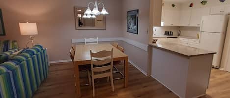 Cocina compacta con una mesa de comedor, sillas, una pequeña isla y un sofá con cojines a rayas.