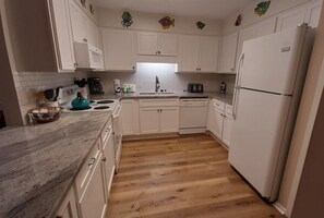 A kitchen with white cabinets, a granite countertop, a stove, a dishwasher, and a refrigerator. - Lazy Days #801 Beach Service Included-2 Chairs and Umbrella 2Bd 2-Bath 1st Fl (Destin)