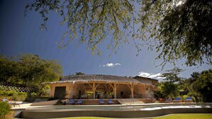 A resort with a pool, lounge chairs, and a thatched-roof building. - Villa Santaluz - Magnificent Ocean View Villa (Coco)
