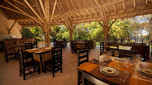 A restaurant with bamboo ceiling and tables set for dining. - Villa Santaluz - Magnificent Ocean View Villa (Coco)