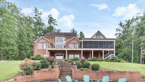 A two-story house with a brick exterior, a covered porch, and a fire pit area with chairs.