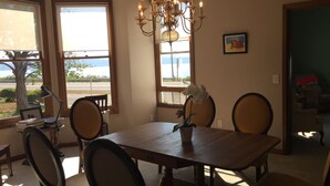A dining room with a wooden table, four chairs, a chandelier, and large windows with a view of the outdoors. - Amazing sunset in front of historic house  (Blaine)