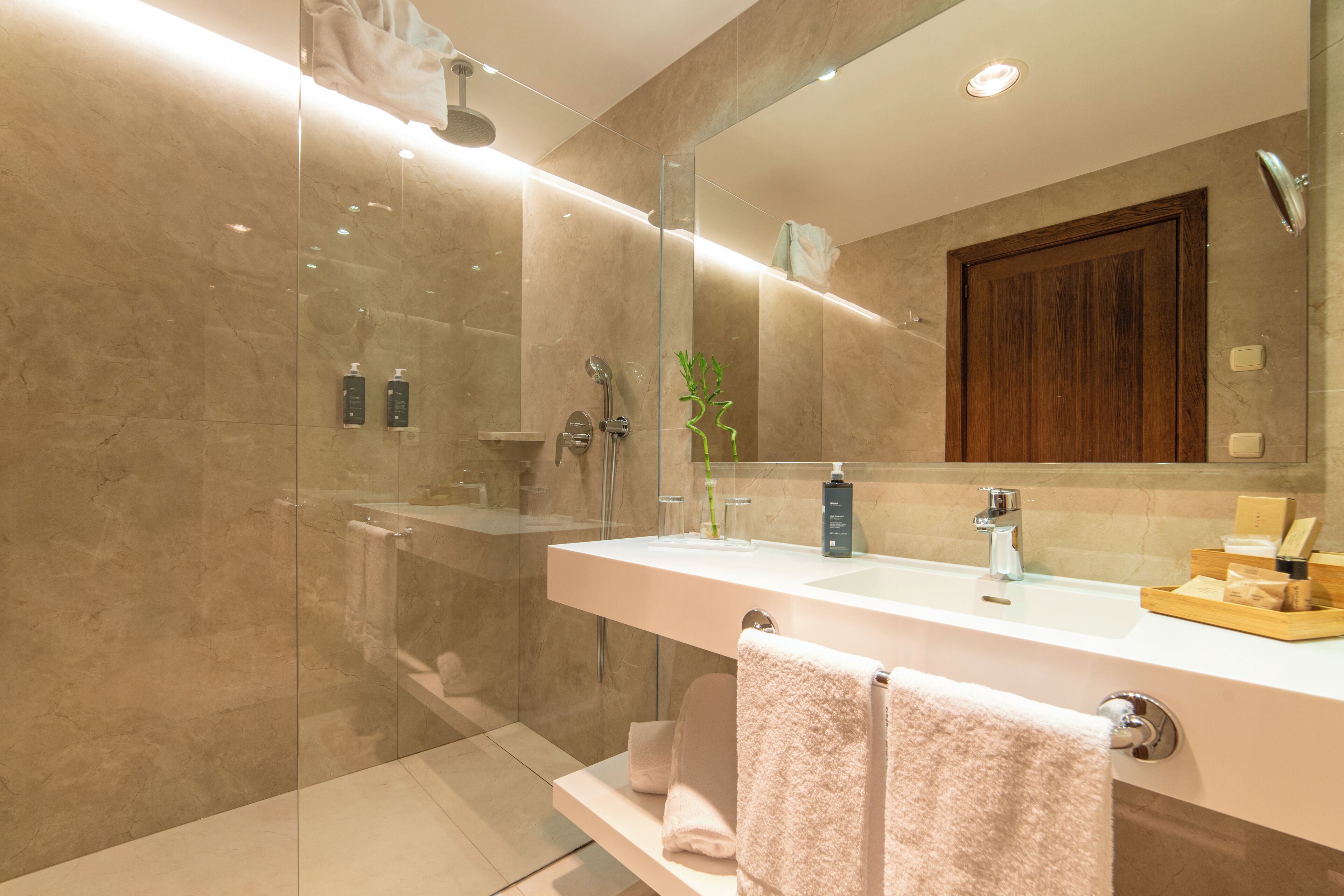 A modern bathroom with a glass-enclosed shower, a large mirror, and a vanity with a sink and towel rack.