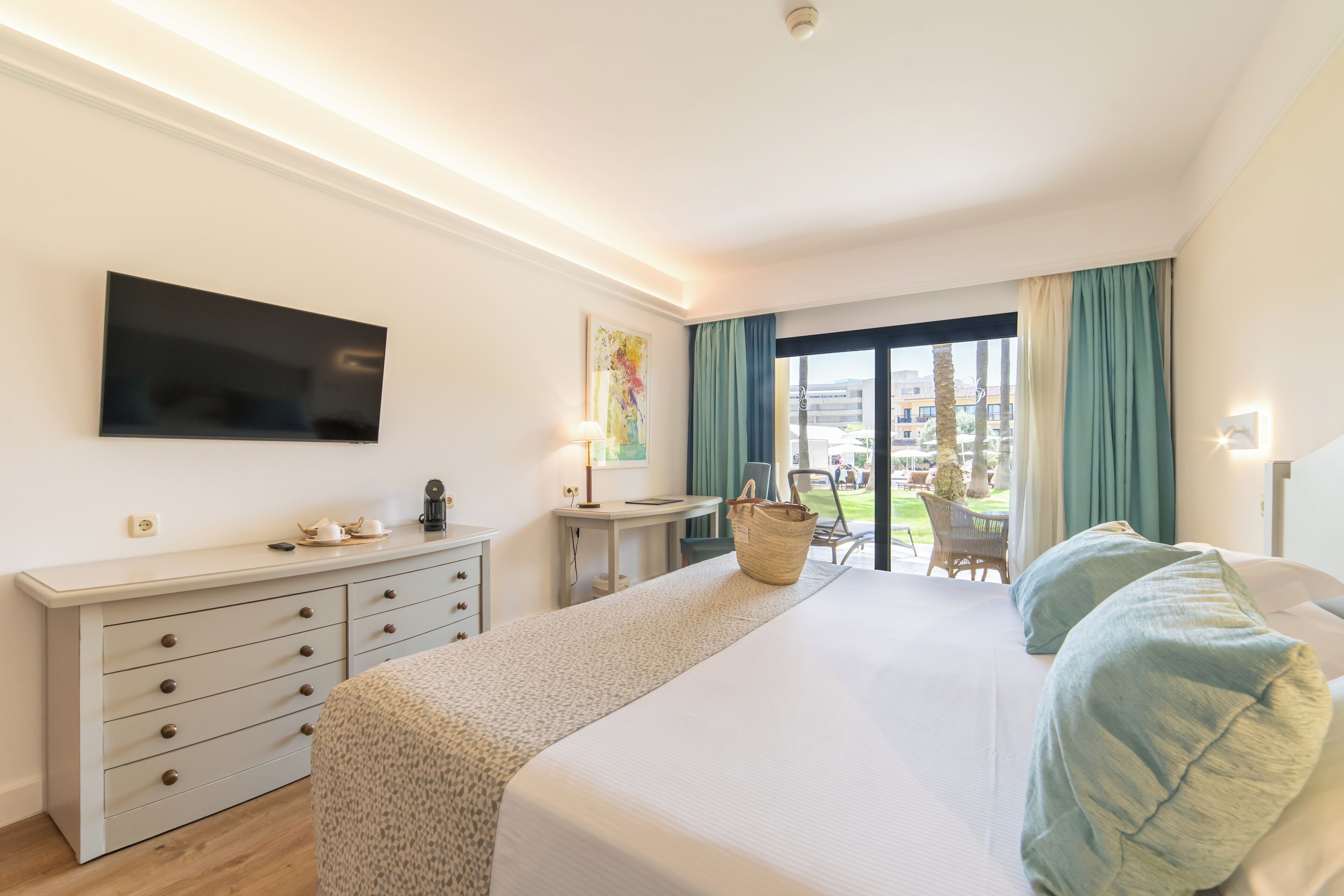 Habitación de hotel con cama, escritorio, televisor y vistas al exterior.
