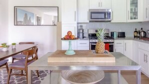 Una cocina moderna con armarios blancos, un microondas y un comedor con mesa y sillas.