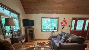 A cozy living room with a brown leather sofa, a patterned rug, and a television on a wooden stand.