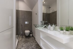 Ein modernes Badezimmer mit Duschkabine aus Glas, Toilette und Waschtisch mit großem Spiegel.