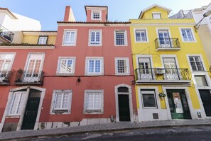Eine Reihe bunter Gebäude mit unterschiedlichen Baustilen, darunter ein gelbes Gebäude mit einem Balkon und ein rotes Gebäude mit einer grünen Tür.
