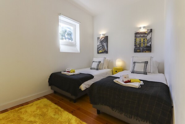 A bedroom with two beds, a window, and artwork on the walls. - Estrela Premium by Homing (Lisbon)