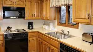 Une cuisine avec des meubles de rangement en bois, un four à micro-ondes, une cuisinière, un évier et un grille-pain.