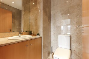 A modern bathroom with a marble sink, wooden cabinets, and a toilet. - Expo Panoramic View by Homing (Lisbon)