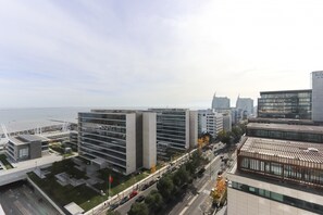 A modern urban area with high-rise buildings, a waterfront, and a busy street. - Expo Panoramic View by Homing (Lisbon)