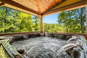 Un jacuzzi con techo de madera y vista a un bosque.