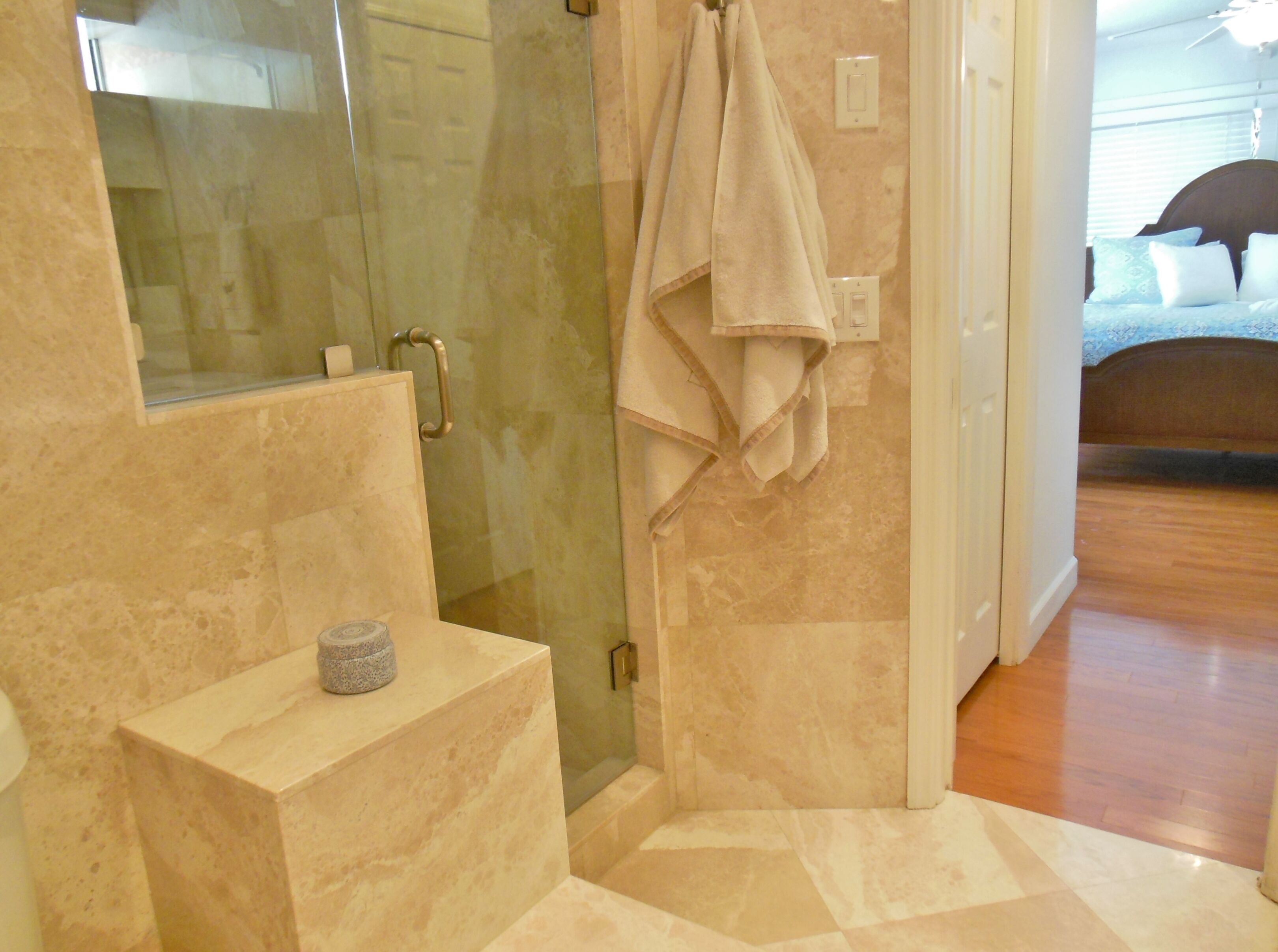 Une salle de bain avec une douche à parois de verre, un comptoir en marbre et une serviette accrochée au mur.